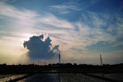 Smoke stack on field against sky during sunset