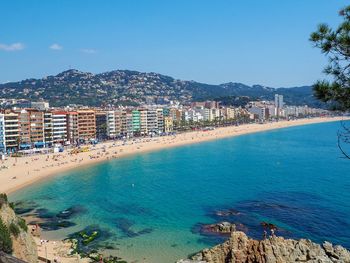 Scenic view of sea by buildings against blue sky