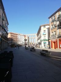 City street by buildings against clear blue sky