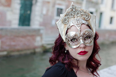 Portrait of woman wearing mask by canal during carnival