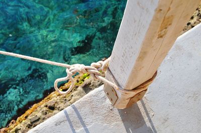 High angle view of rope tied up on pole against sea