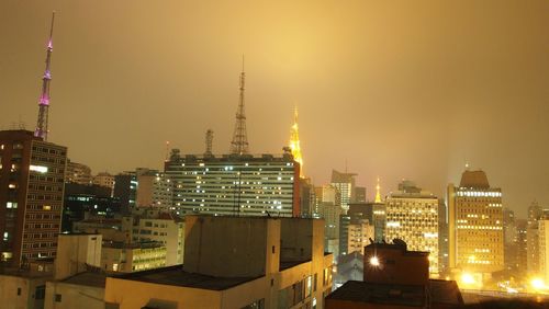 Illuminated buildings in city against sky at night