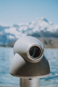 Close-up of coin-operated binoculars by sea against sky