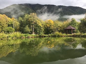 Scenic view of lake by trees and mountains against sky