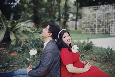 Portrait of happy pregnant woman sitting with boyfriend at park