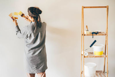 Rear view of woman standing against wall