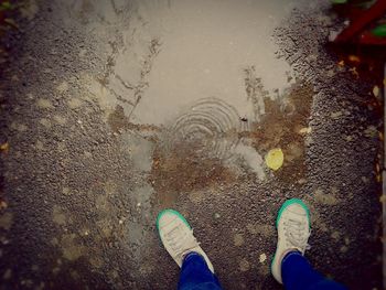 Low section of man standing on puddle