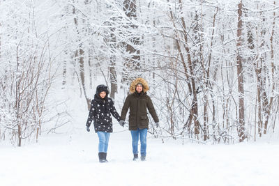 Full length portrait of two women standing on snow covered landscape