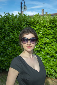 Portrait of woman wearing sunglasses while standing against plants