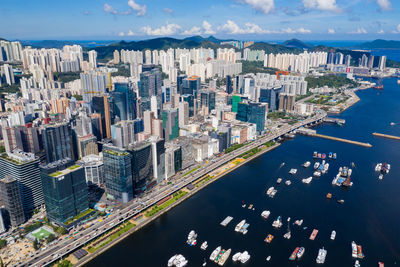 Aerial view of modern buildings by sea against sky