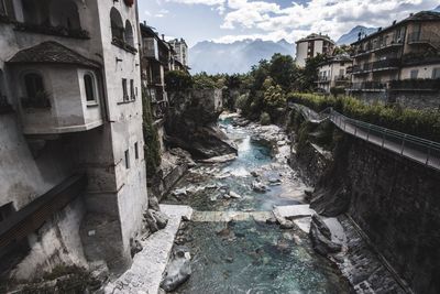 Canal amidst old buildings against sky