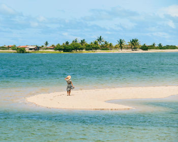 Rear view of woman walking at beach against sky