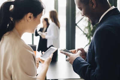 Business coworkers using mobile phone in meeting at office