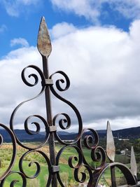 Close-up of metal gate against sky