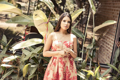 Portrait of young woman standing against plants