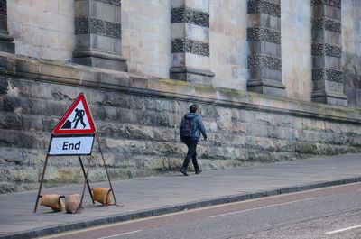 Man walking on road by building