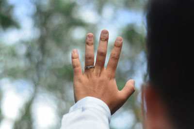 A man's hand with a ring in a pine forest