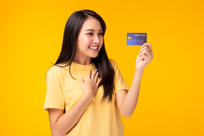 Portrait of smiling woman standing against yellow background