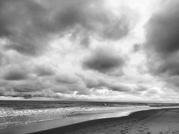 Scenic view of beach against cloudy sky