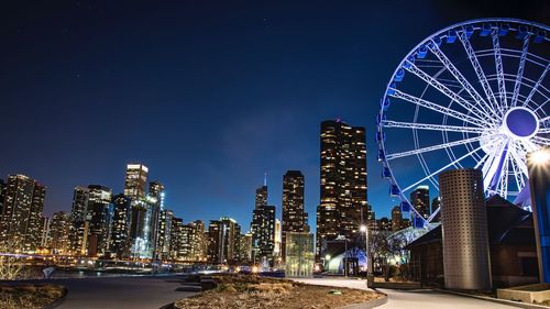 Low angle view of illuminated ferris wheel against sky at night