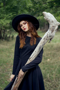 Portrait of young woman wearing hat standing on field