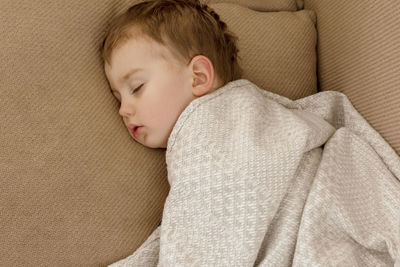 Little, cute caucasian boy sleeping on couch at home. child taking day nap. kid resting, relaxing. 