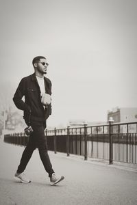 Full length of man standing on railing against sky