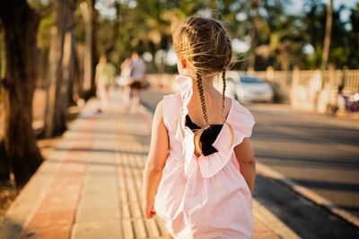 Rear view of girl walking on sidewalk