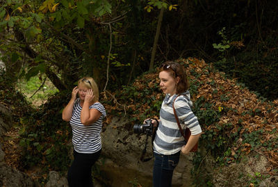 Full length of friends standing on field in forest