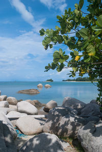 Rocks at beach against cloudy sky