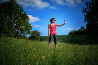 Woman with arms raised on field against sky