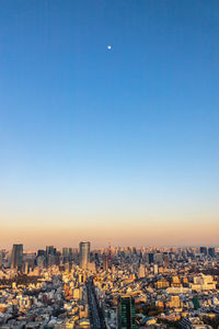 Aerial view of buildings in city against clear blue sky