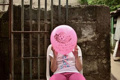 Low section of girl standing with pink balloons