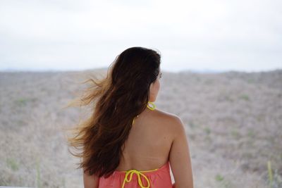 Woman looking away while standing on beach