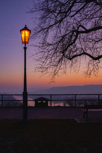 Street light by sea against sky during sunset