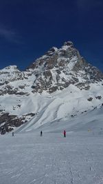 People skiing on snowcapped mountain against sky