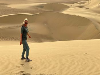Portrait of mature woman standing on sand dune in desert