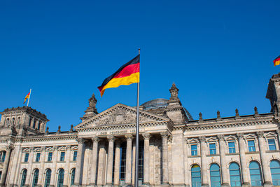 Low angle view of flags against blue sky