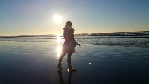 Woman standing on shore against sky