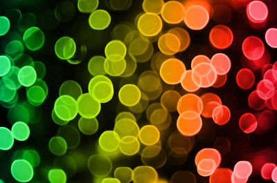 Defocused image of multi colored illuminated lights against black background