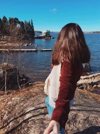 Rear view of woman standing by sea against sky