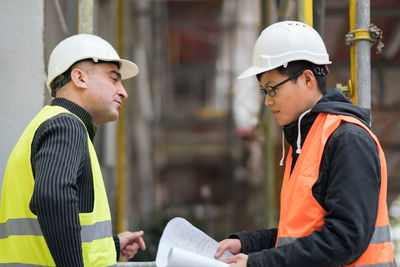 Engineers discussing while standing at construction site