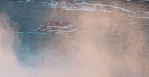 High angle view of ship sailing on river during foggy weather