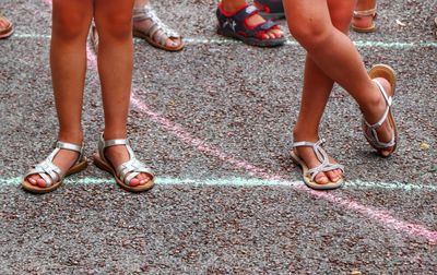 Low section of girls standing on footpath