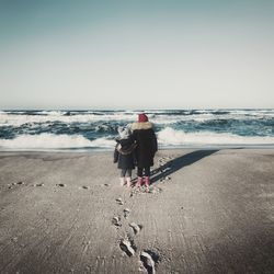 Rear view of man on beach against clear sky