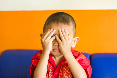 Close-up portrait of boy with hands covering face