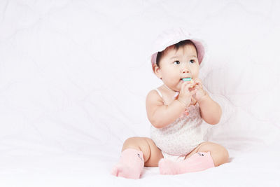Cute baby girl sitting on bed at home