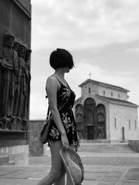 Woman standing against church and sky in city