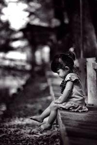 Side view of girl sitting on pier