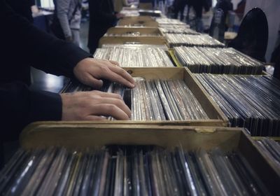 Midsection of man searching record in container